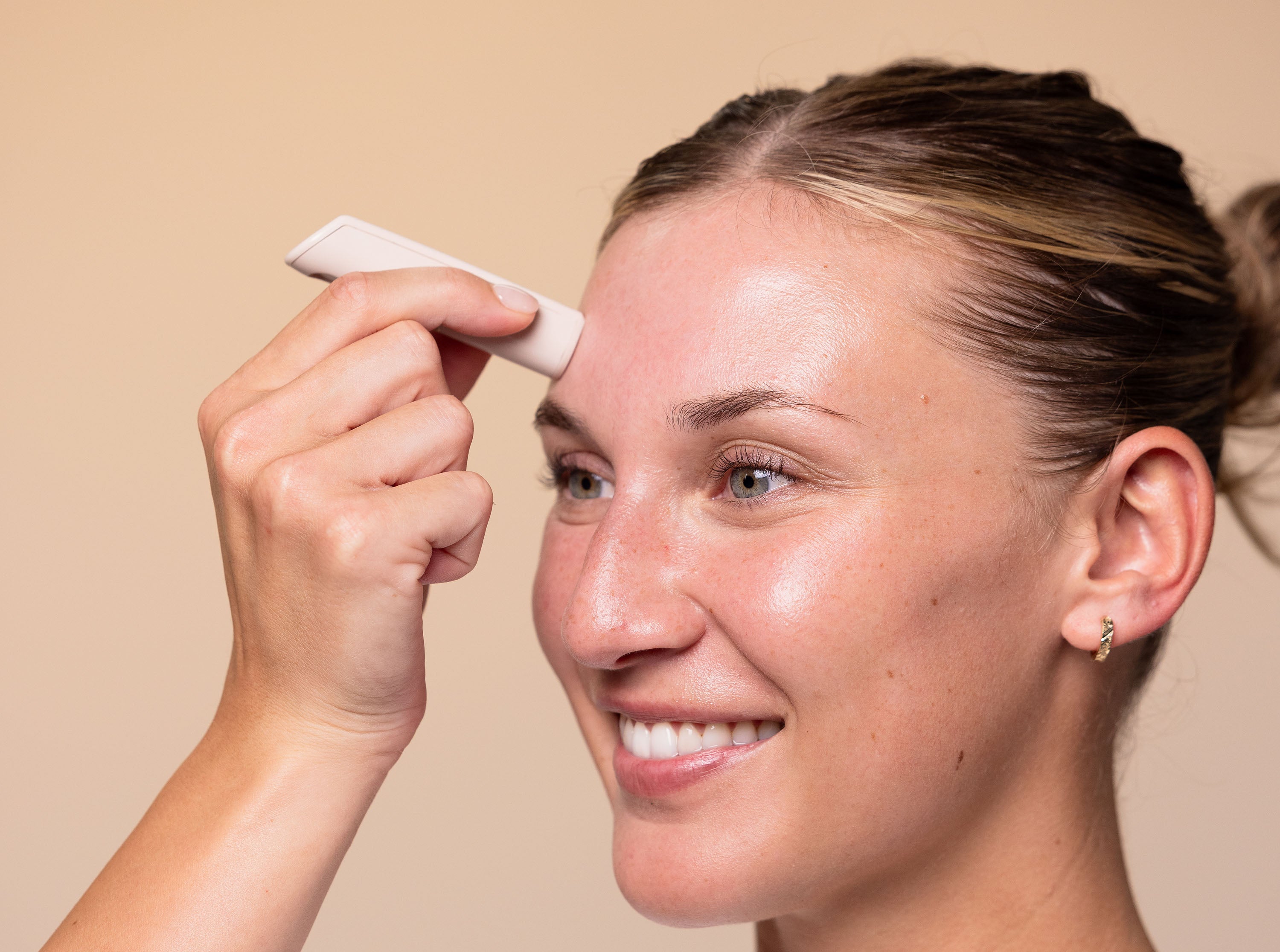 a female model using the boldhue wand to scan her forehead skin