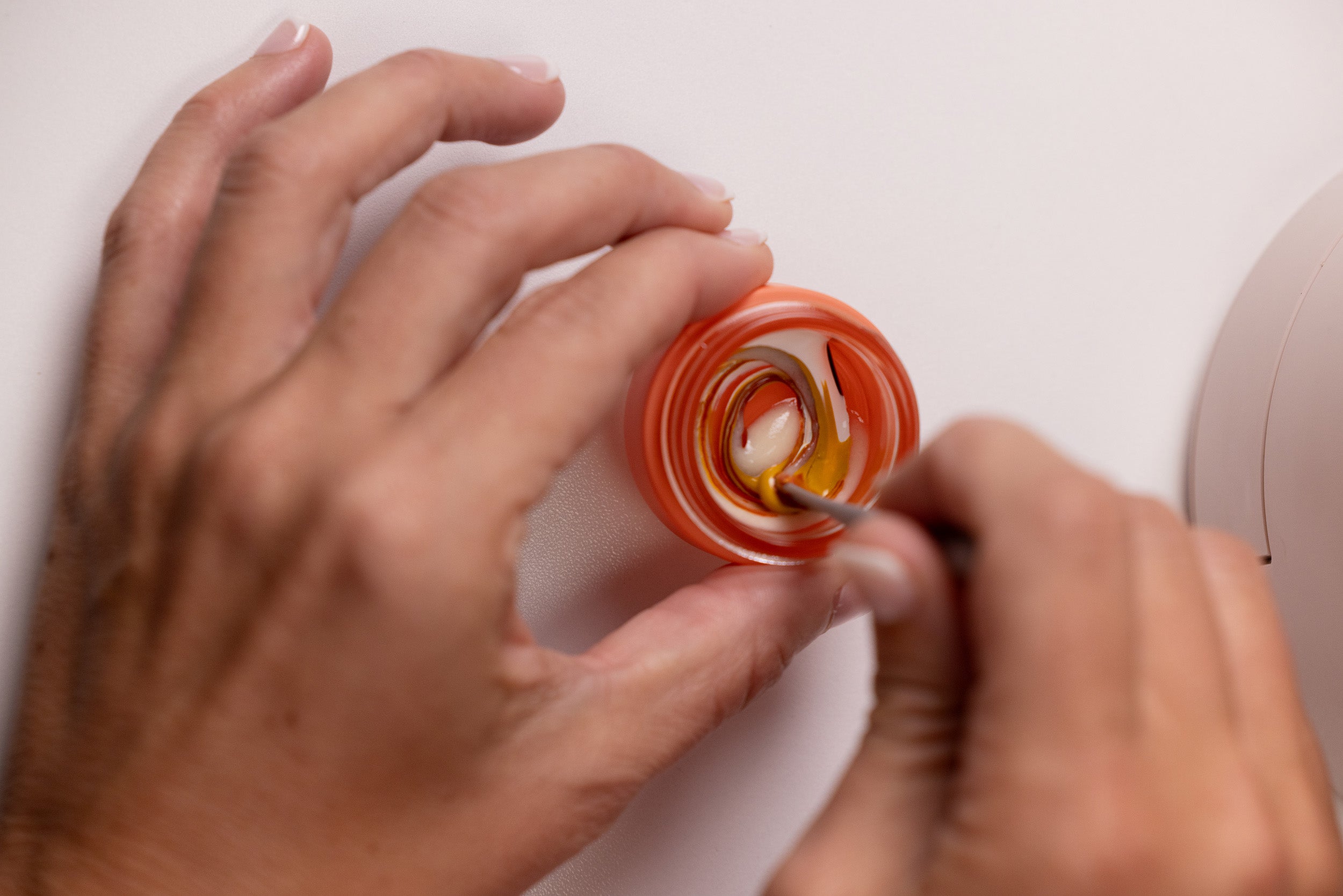 two hands mixing a freshly made foundation with the mixing spatula revealing swirls of color