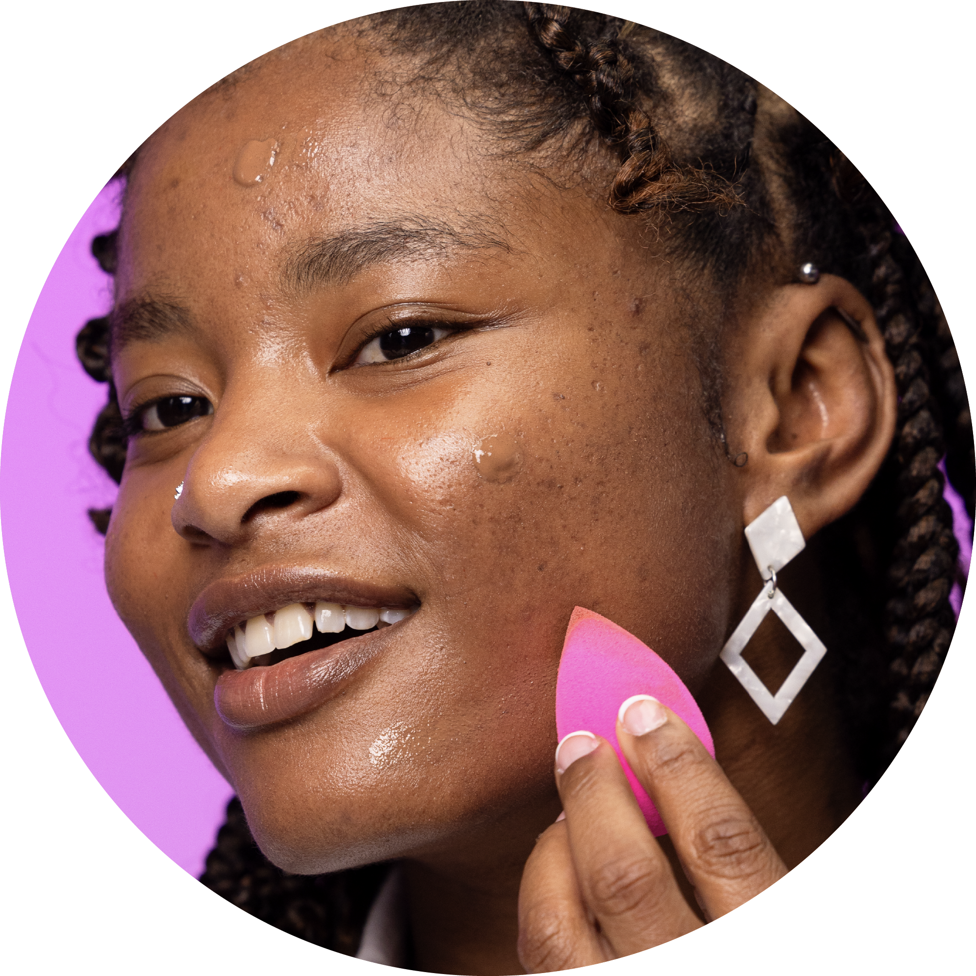 a female model applying boldhue foundation to her face using a beautyblender sponge